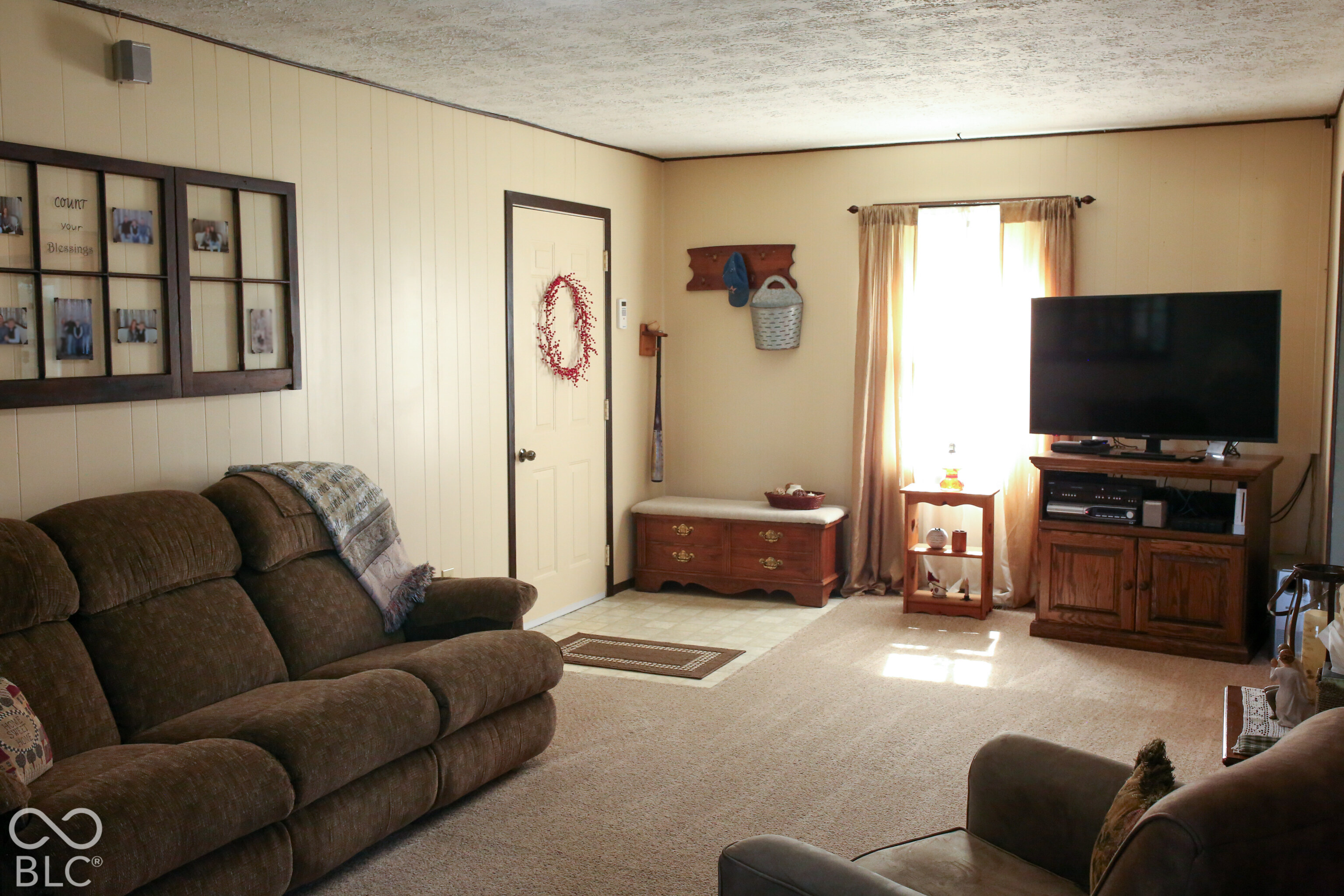 Living room with brown reclining sofas and a TV beside a bright curtained window.
