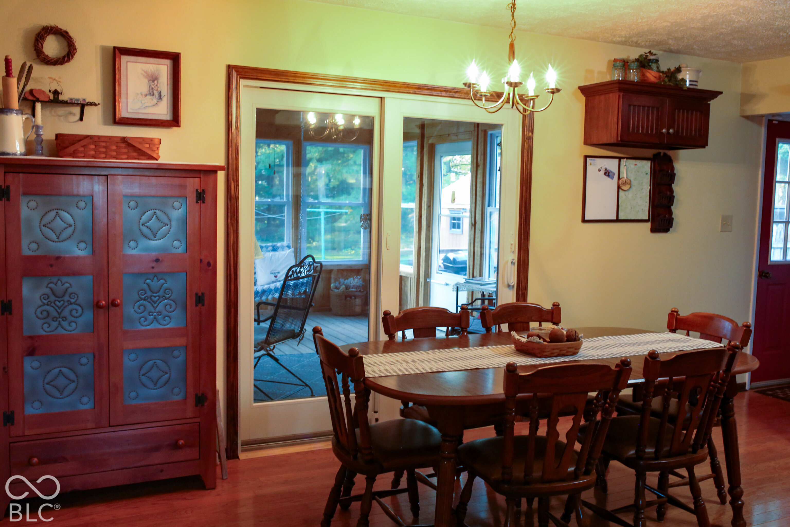 Dining room with a wooden table, red cabinet, and sliding doors to a sunroom.