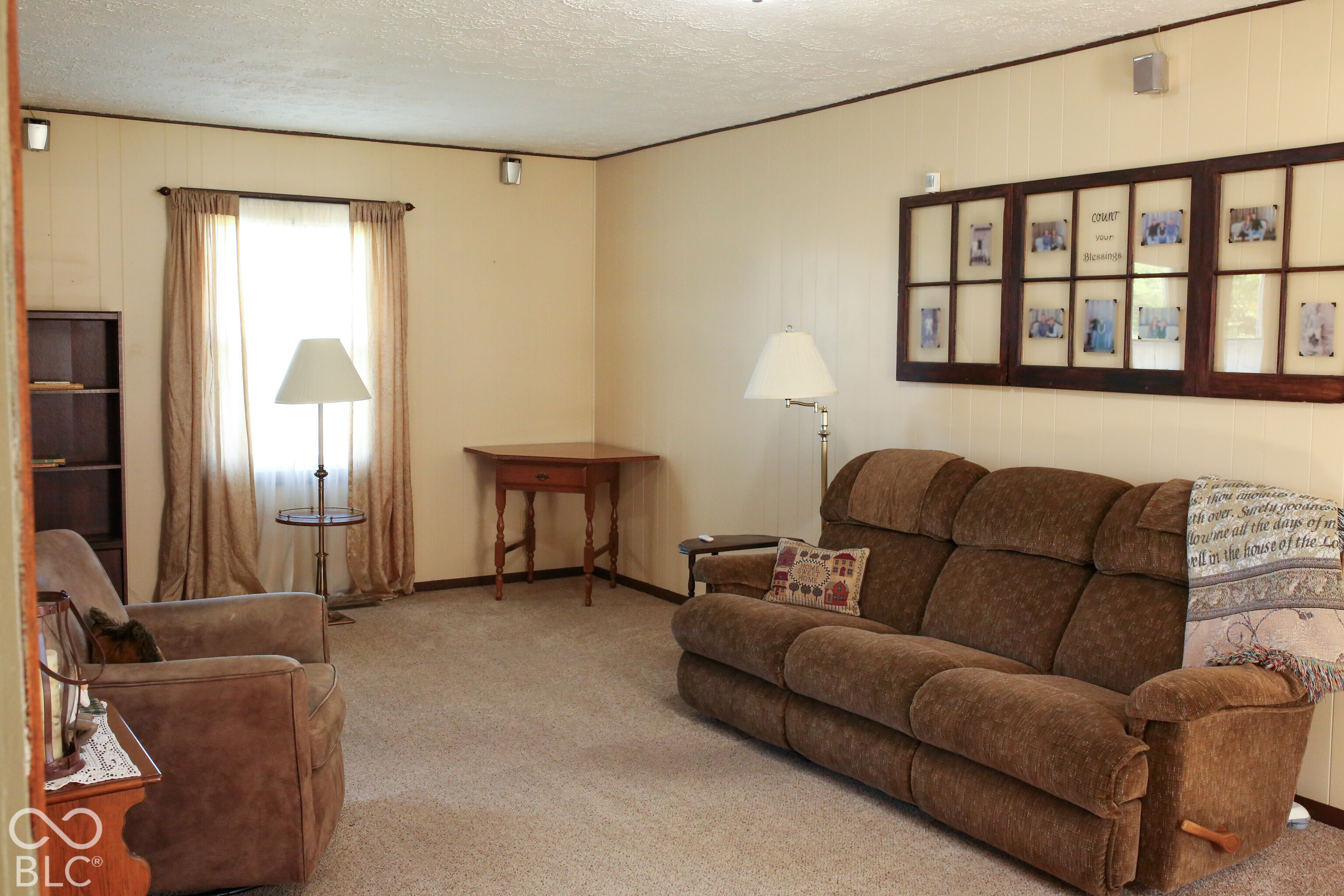 Furnished living room with brown reclining sofa, matching armchair, and framed family photos.