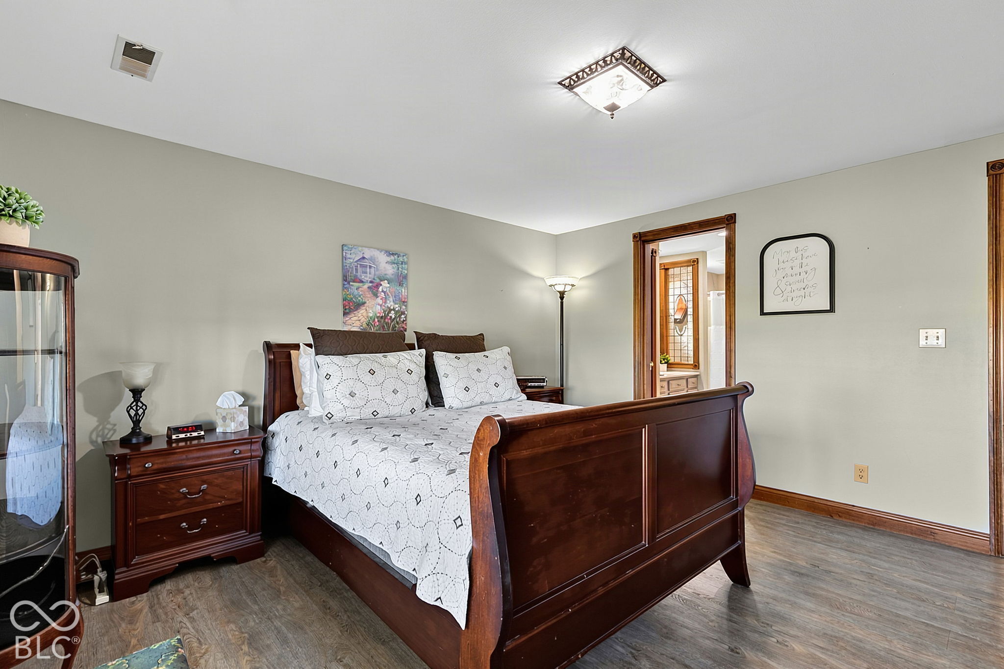 Bedroom with a dark wood sleigh bed, white patterned bedding, and a doorway to an adjoining room.