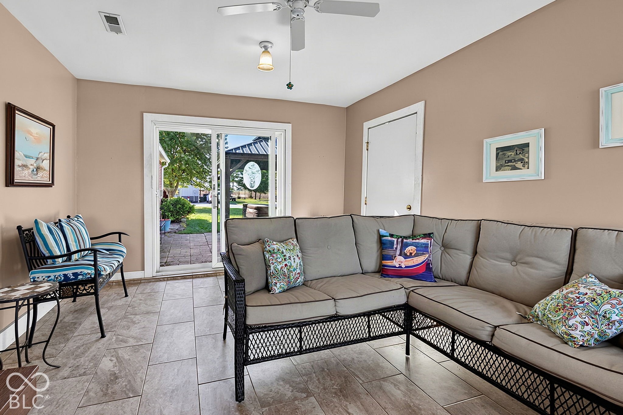 Furnished sunroom with a gray sectional sofa and sliding doors to a patio and yard.