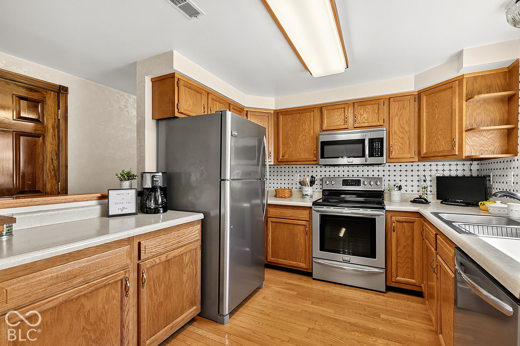 Kitchen with honey-oak cabinets, stainless steel appliances, and a black-and-white tile backsplash.