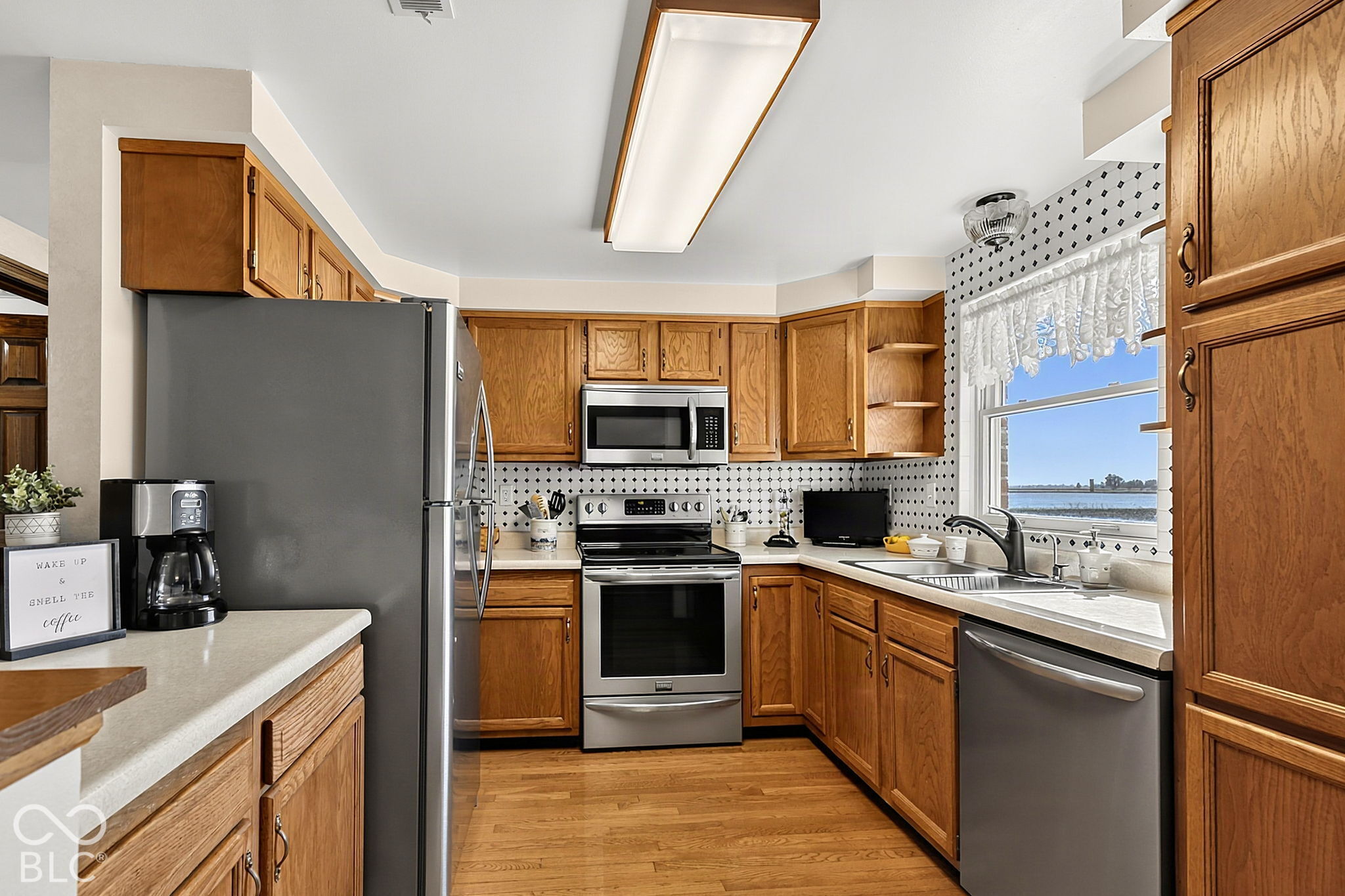 Kitchen with oak cabinets, stainless steel appliances, patterned tile backsplash, and a water view through the window.