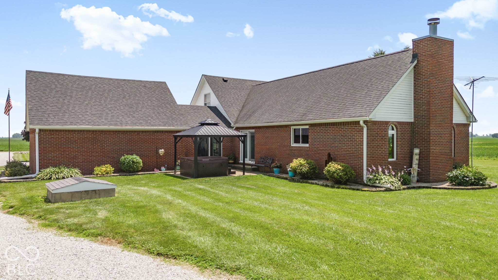 Red-brick home with a tall chimney and gazebo-covered hot tub in the backyard.