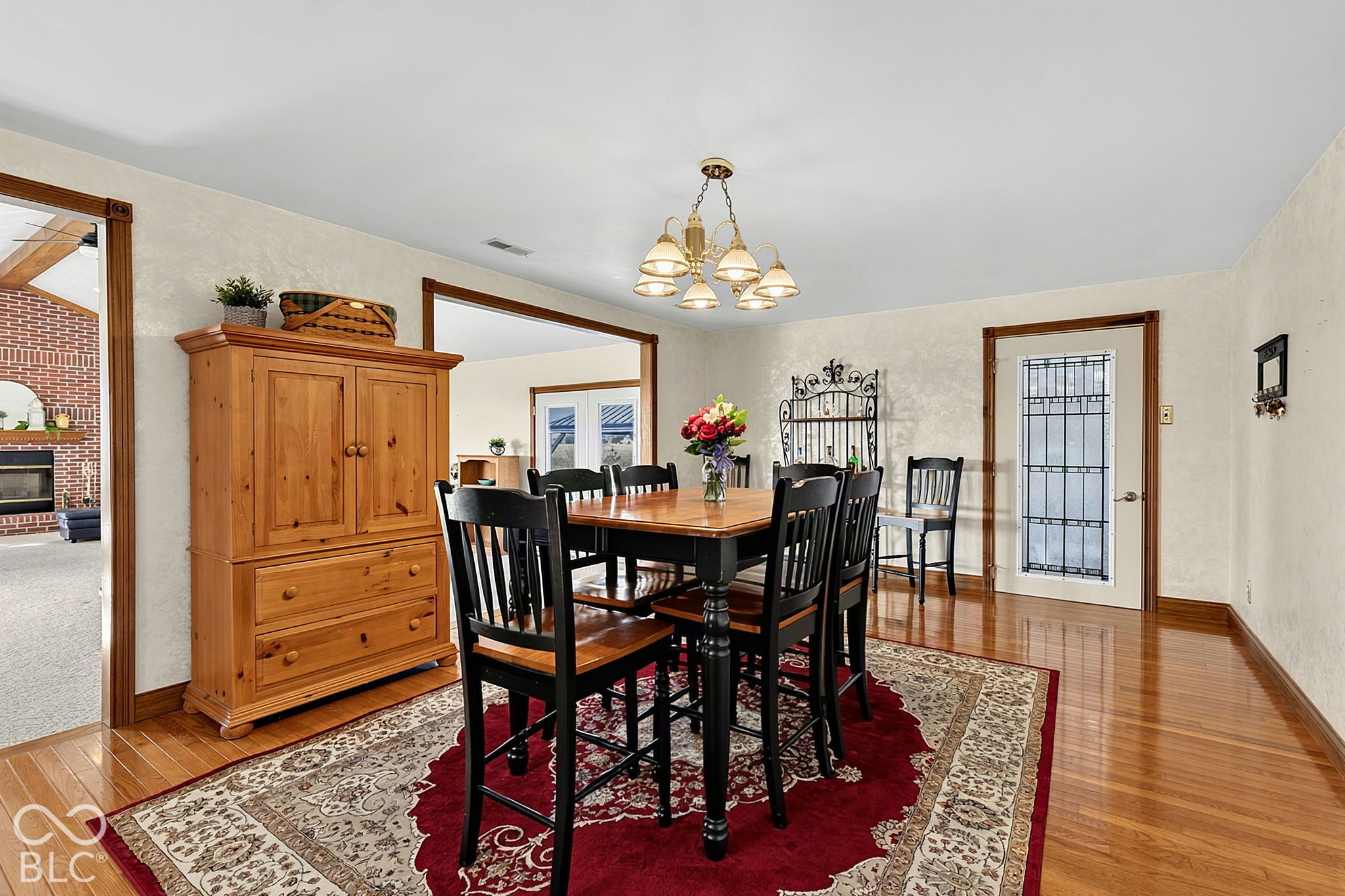 Dining room with a dark wood table, black chairs, red patterned rug, and large wooden hutch.