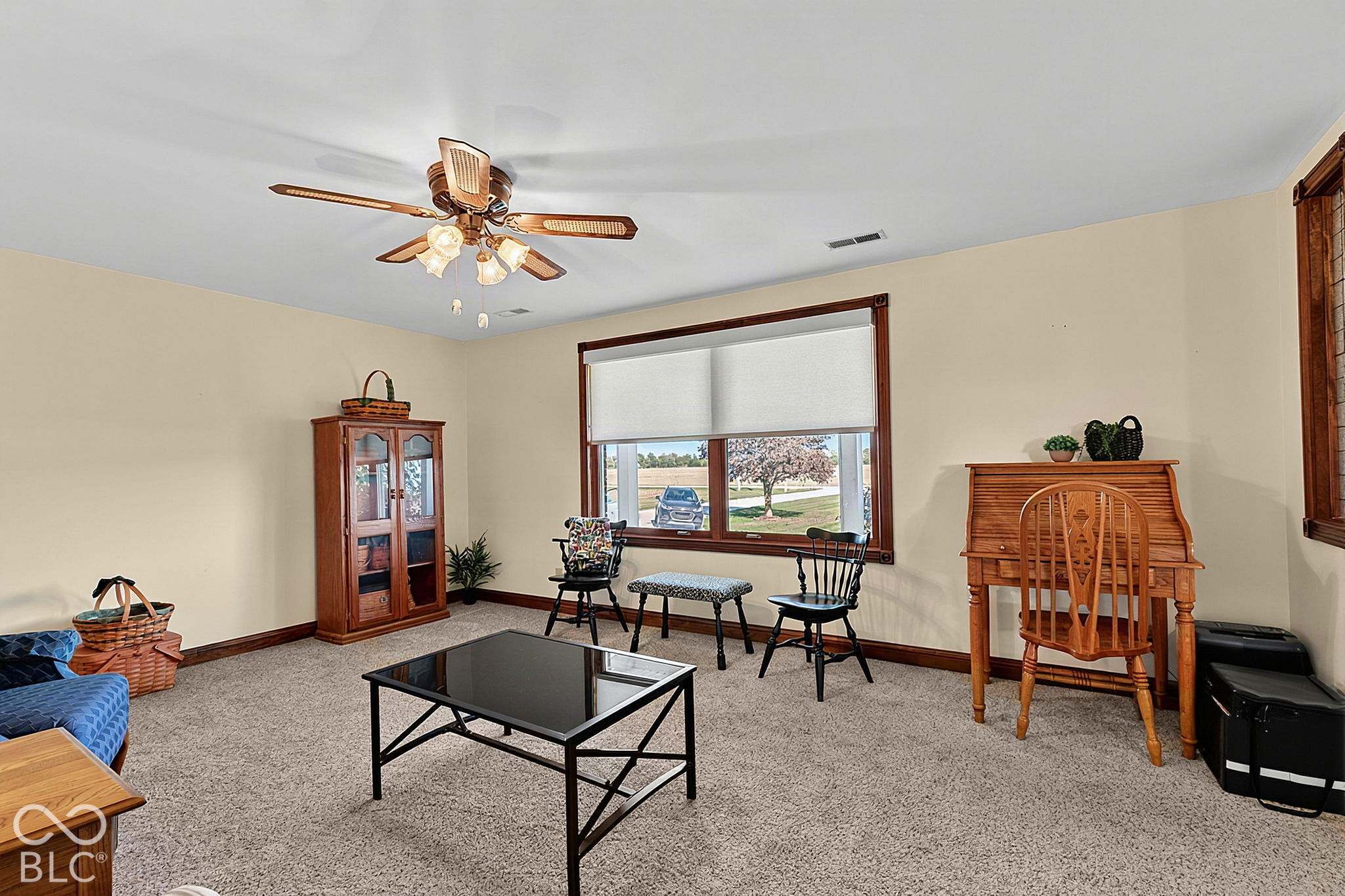 Furnished living room with a large window, wood furniture, and a ceiling fan.