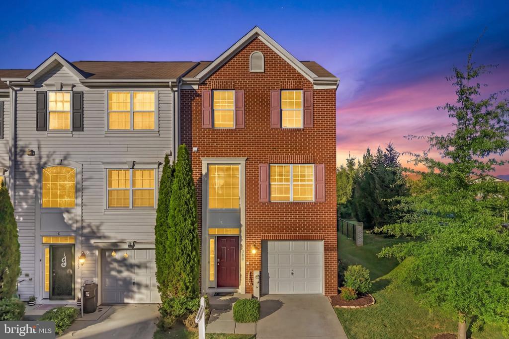 Townhouse with red brick facade and lit windows at dusk.