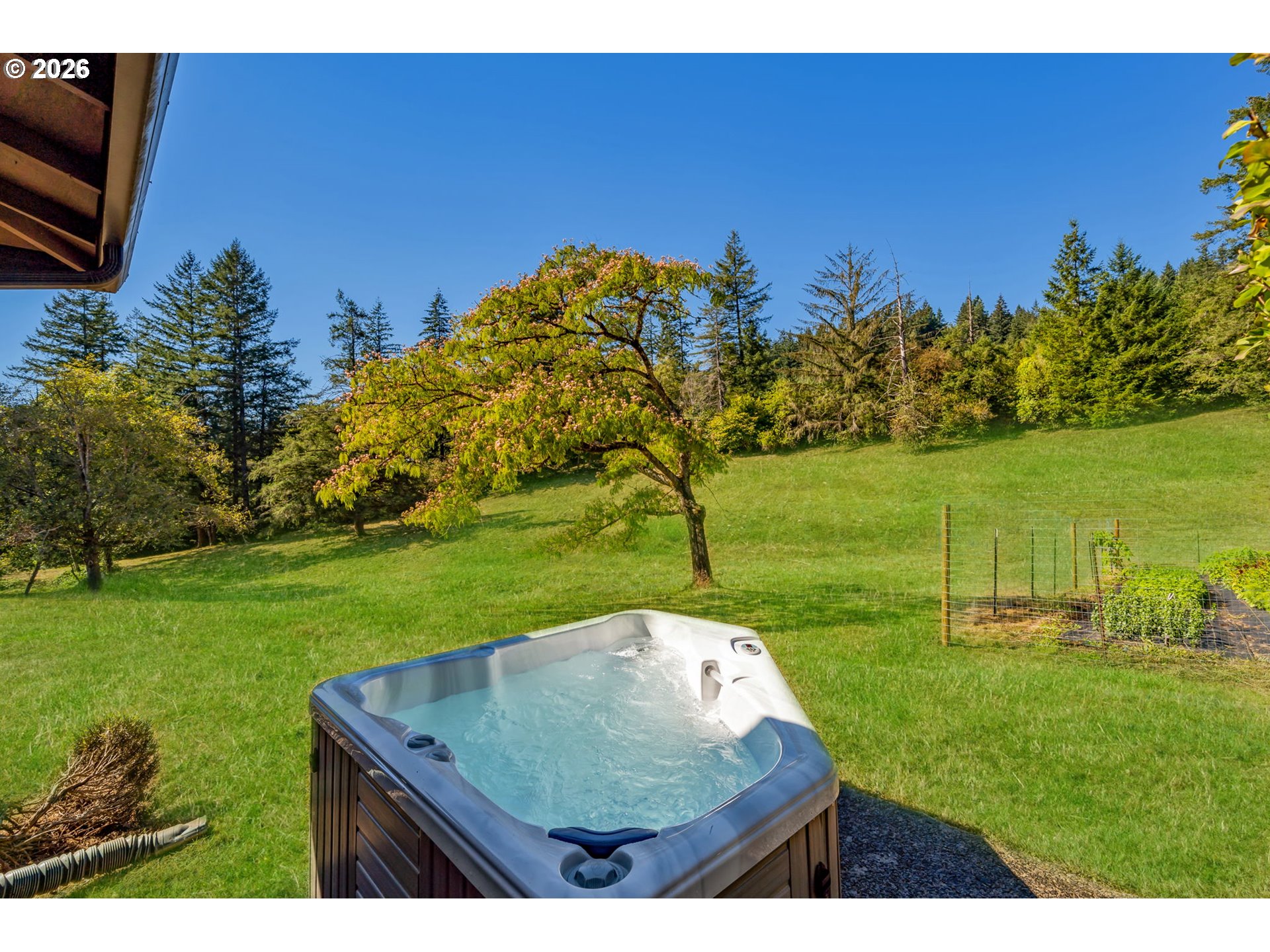 Outdoor hot tub beside a sloping lawn and mature trees
