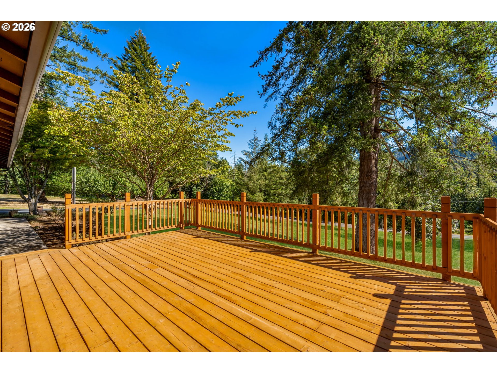 Wooden deck with matching railings overlooking a tree-lined yard.