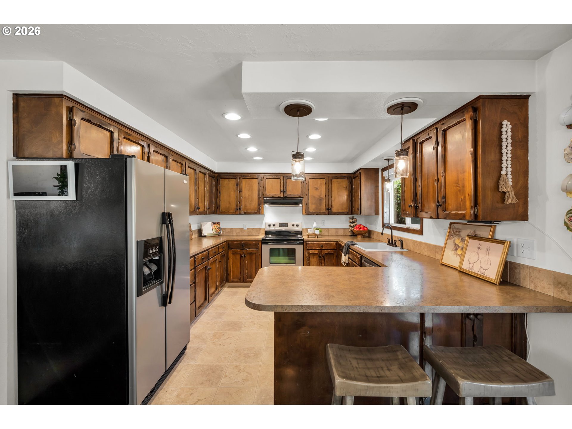 Kitchen with dark wood cabinets, stainless appliances, and a large breakfast bar island.