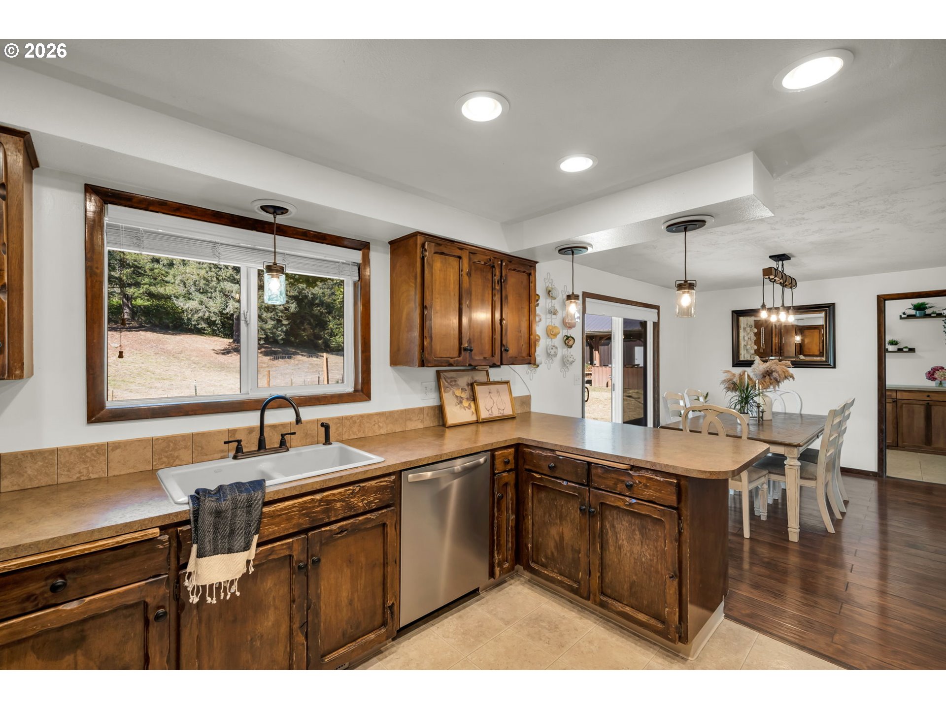 Kitchen with rustic wood cabinets, tan countertops, farmhouse sink, and adjoining dining area.