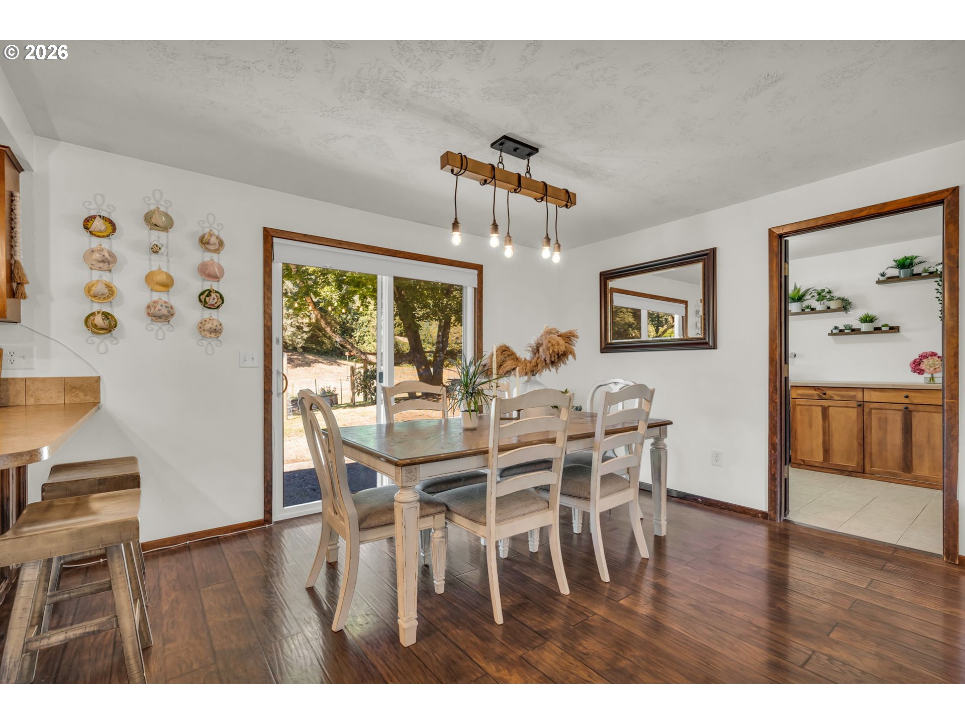 Dining room with a wooden table, sliding glass doors, and dark wood-look flooring.