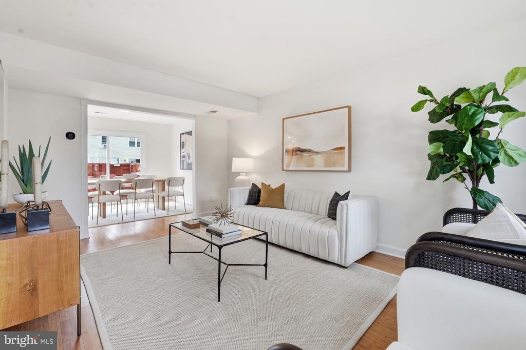 Furnished living room with a white channel-tufted sofa, light rug, and doorway to the dining area.