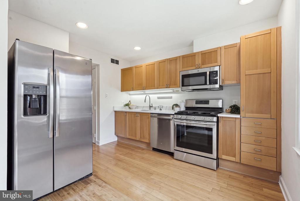 Kitchen with light wood cabinets, stainless steel appliances, and hardwood floors.