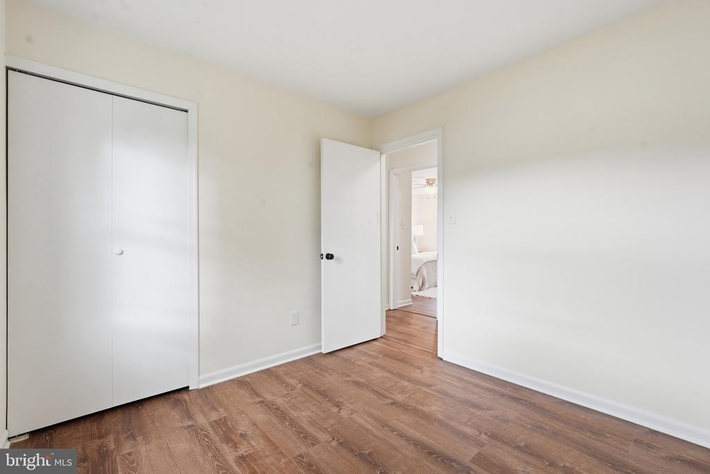 Vacant room with a white sliding-door closet, wood-look flooring, and an open doorway.