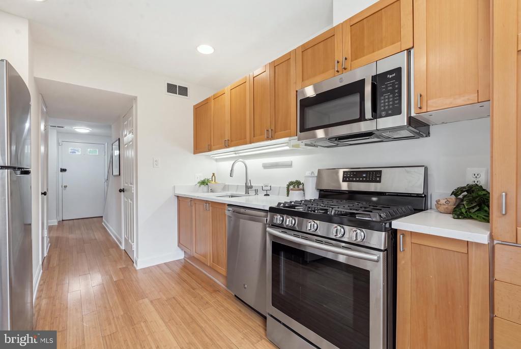 Kitchen with warm wood cabinets, hardwood floors, and stainless steel appliances.