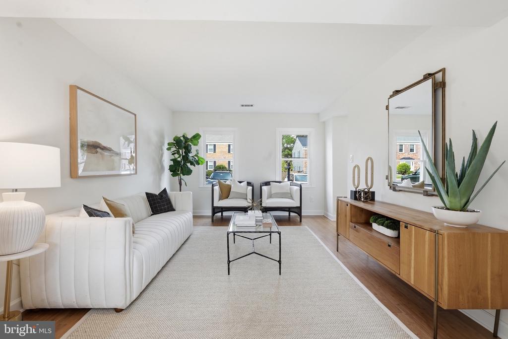 Staged living room with white seating, a pale rug, and a long wood media console.