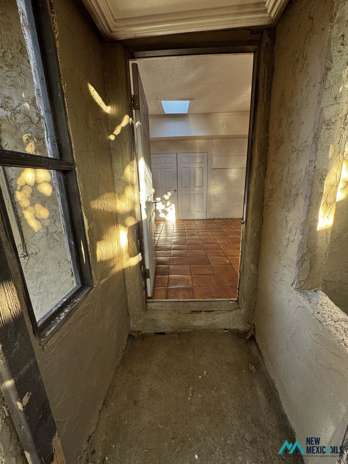 Entry vestibule opening to a tiled foyer with double doors and a skylight.