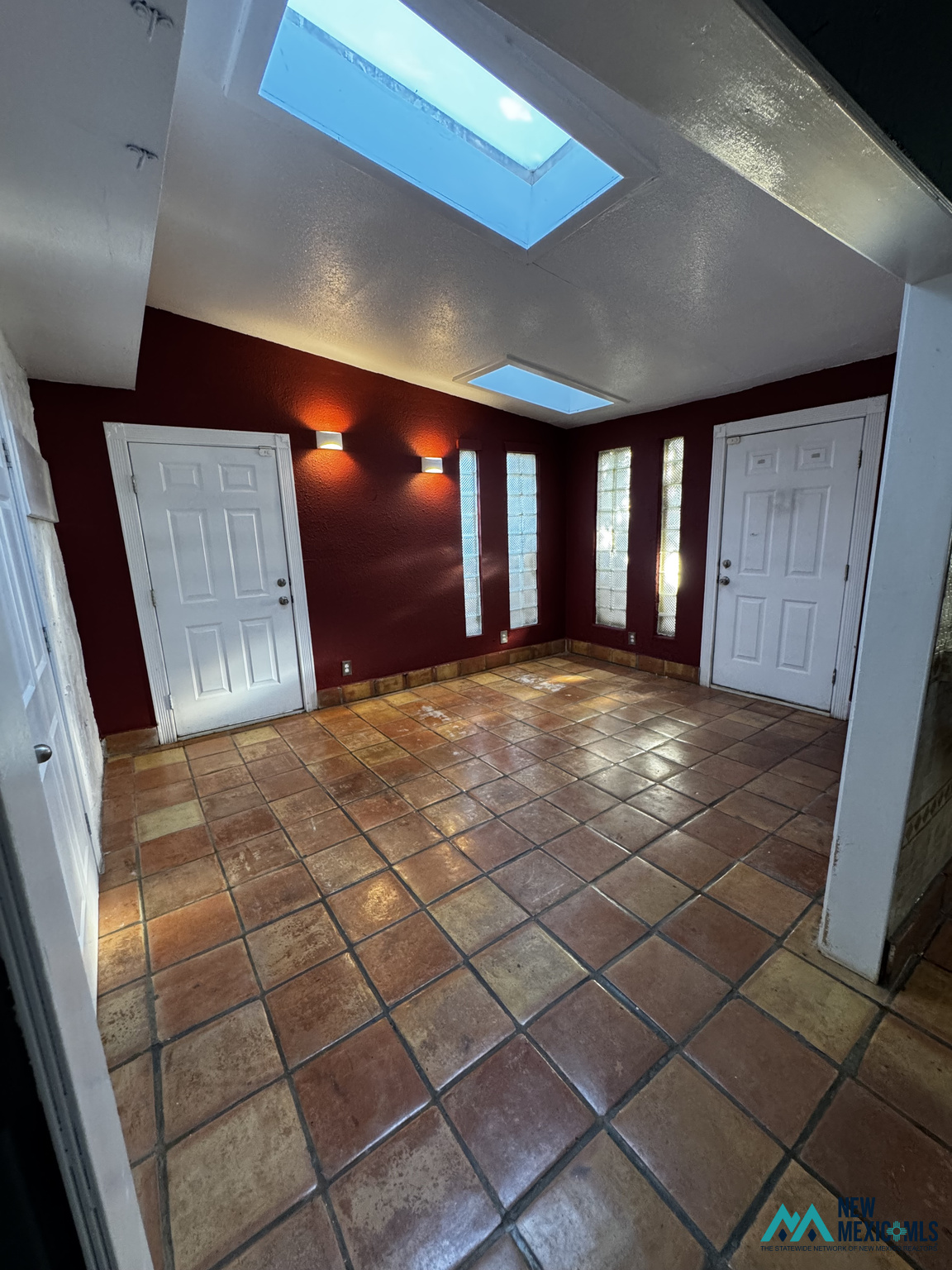 Entryway with terracotta tile flooring, burgundy walls, glass-block windows, and two skylights.