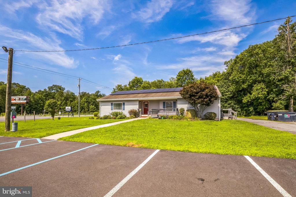 Single-story building with solar panels, a covered entrance, and a parking lot across the front lawn.