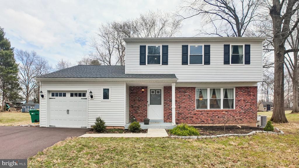 Two-story house with white siding, red brick, dark shutters, and an attached garage.