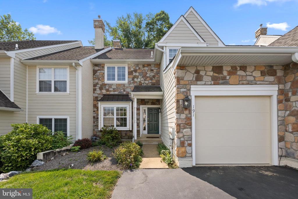 Townhouse exterior with a stone facade, white garage door, and green front door.