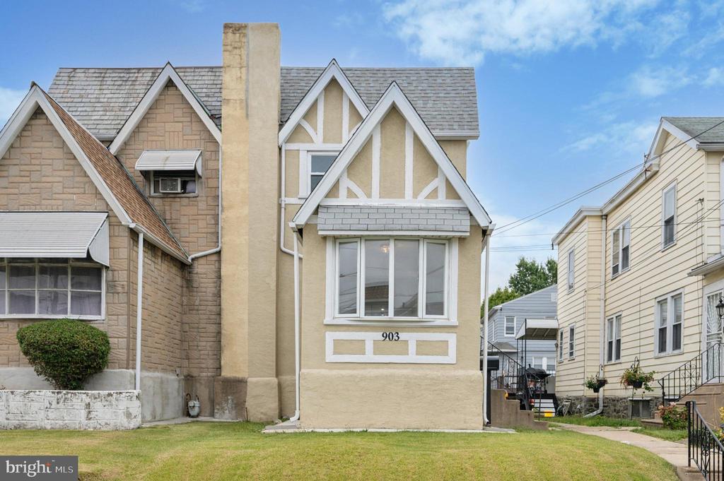 Beige gabled house with white trim and street number 903, between neighboring homes.