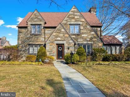 Stone-front two-story home with steep gables and a paved walkway to the front door.