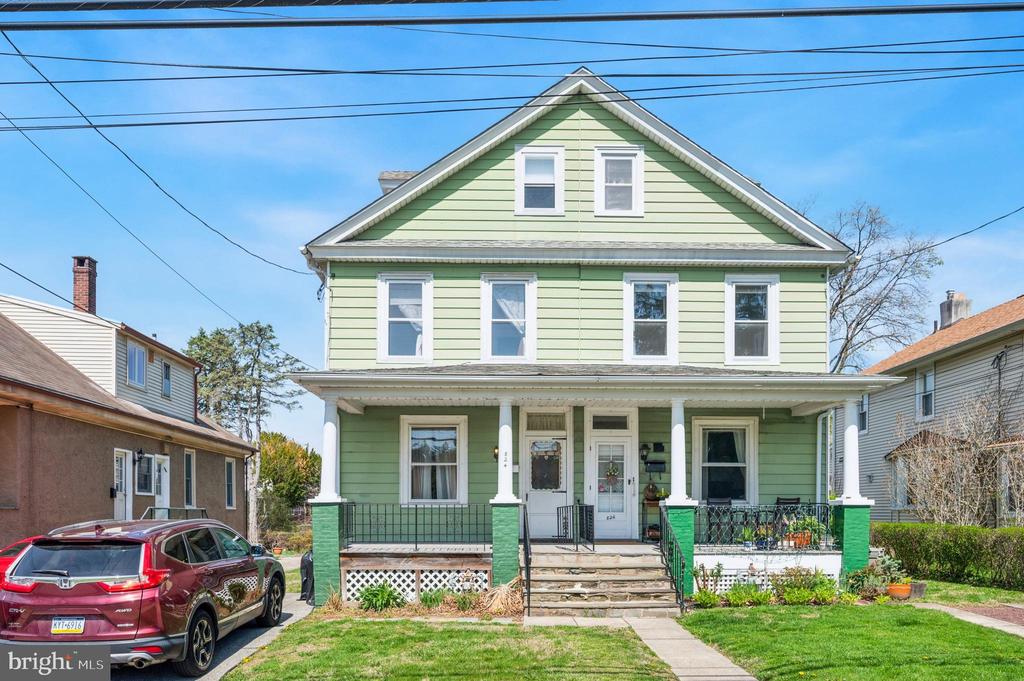 Pale green two-story house with a covered porch and red SUV in the driveway.