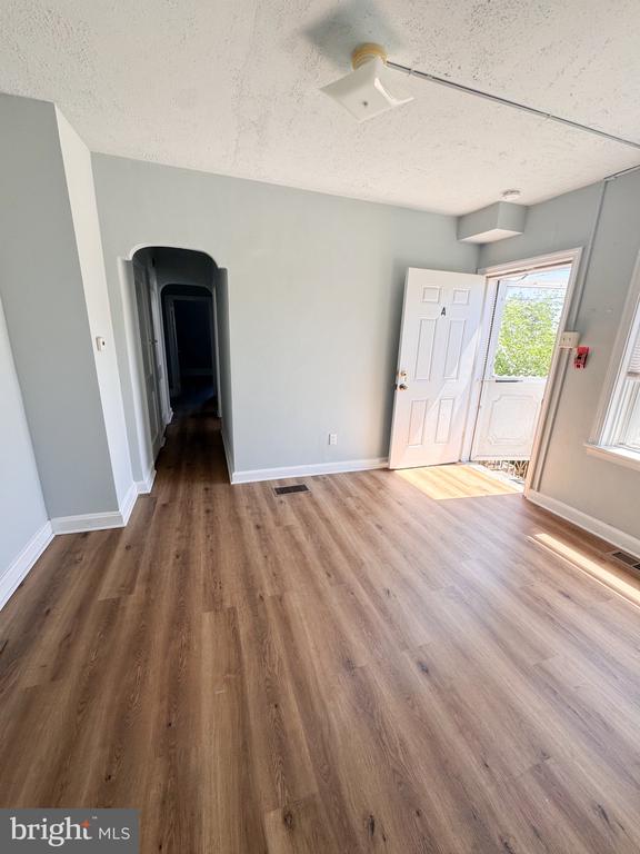 Empty room with wood-look flooring, gray walls, and an open exterior door.