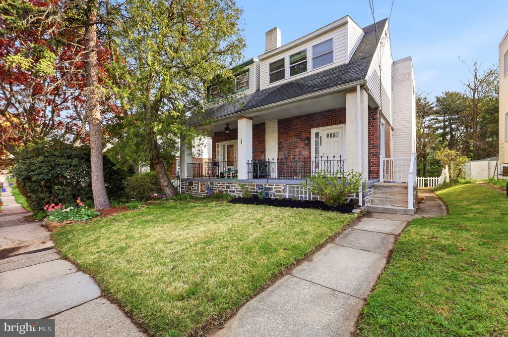 Two-story brick and white-sided home with a covered porch, dormer windows, and a front lawn.