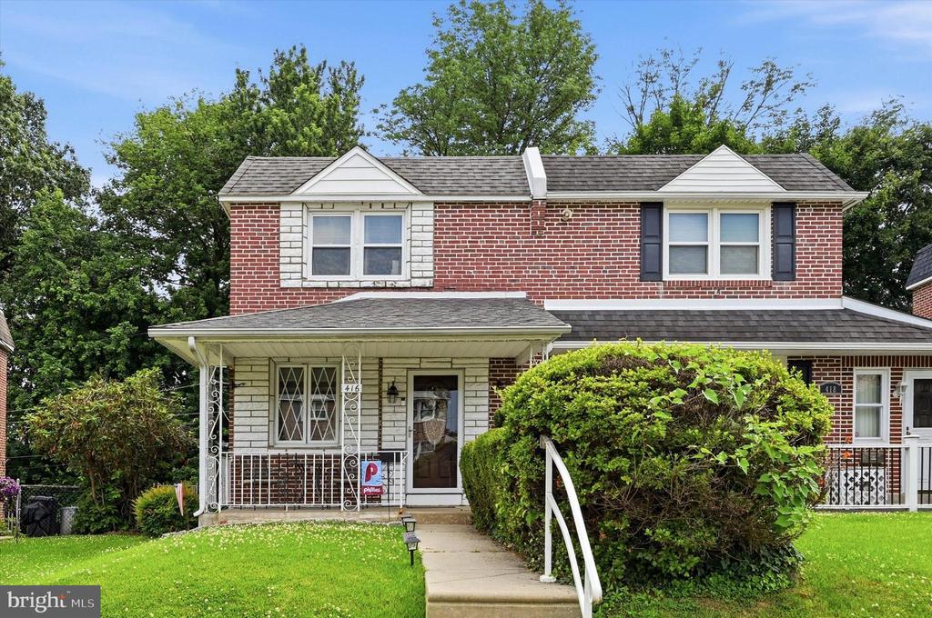 Brick two-story home at 416 with a covered porch and shrubs along the front walkway.