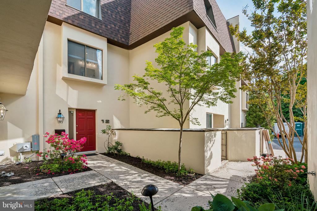 Townhouse entrance with a red door, landscaped walkway, and unit number 12.