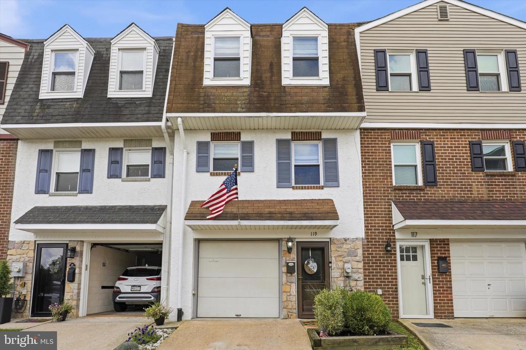 Townhouse at 119 Sutcliffe Lane with an American flag, attached garage, and stone accents.