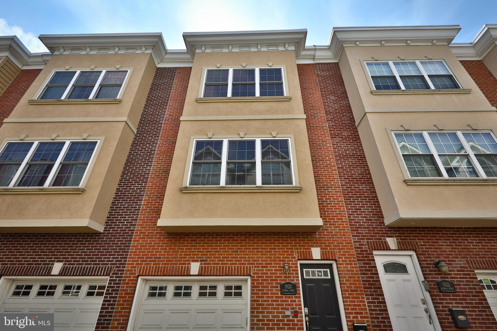 Attached brick and stucco townhouses with white-trimmed windows and garage doors.