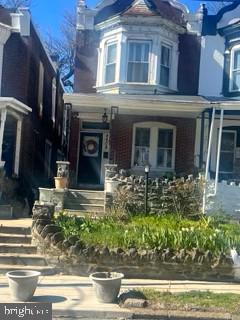 Brick row house with a projecting bay window, front steps, and a small garden.