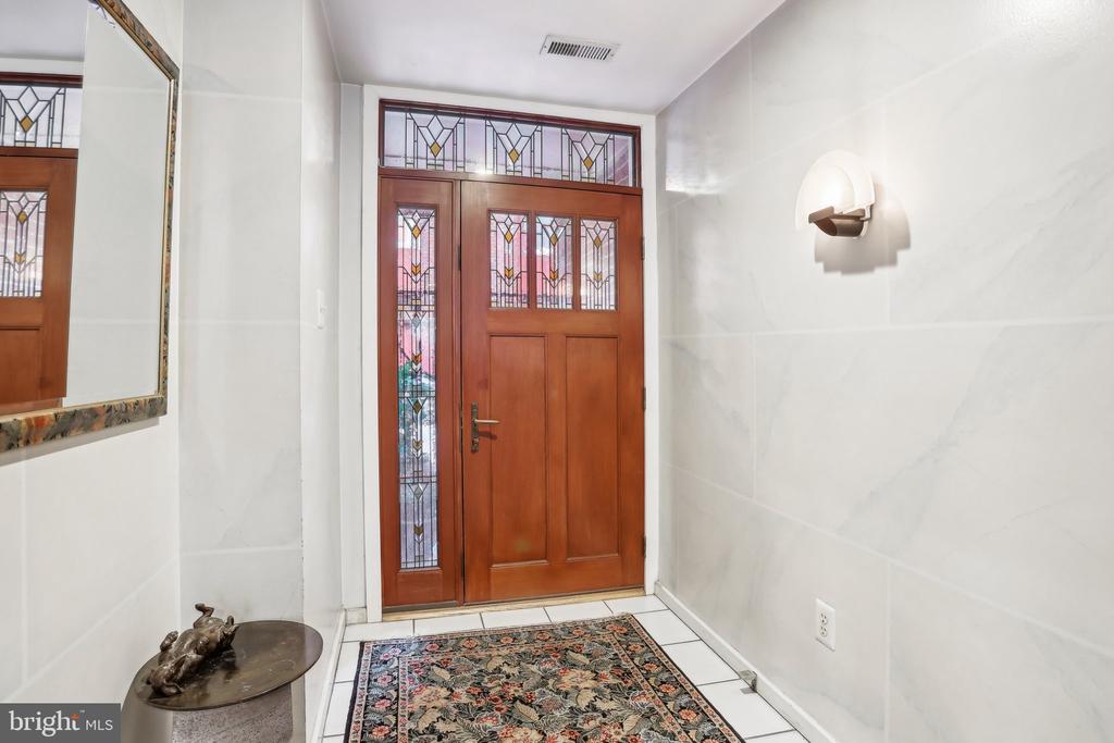 Foyer with a wood entry door featuring decorative stained-glass panels and a patterned runner rug.