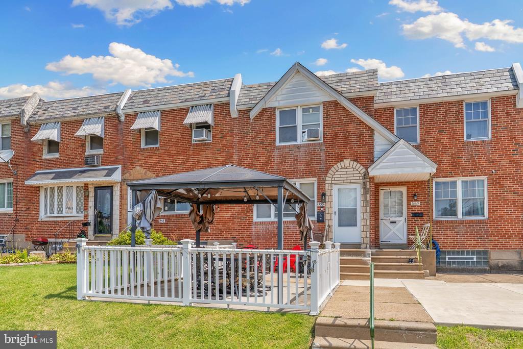 Red-brick townhouse row with a white-fenced patio and canopy.