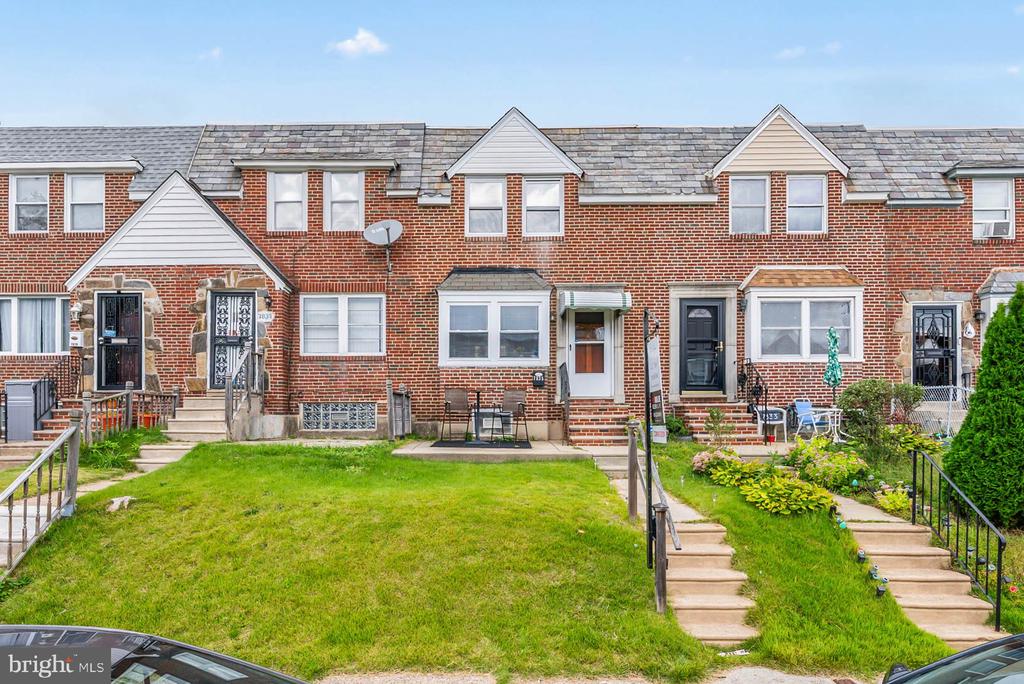Red-brick rowhomes with slate roofs, grassy front yards, and garden steps.