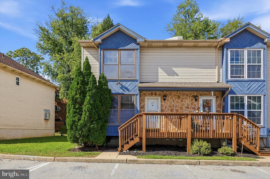 Two-unit townhouse with blue trim, stone accents, and a shared wooden front deck.