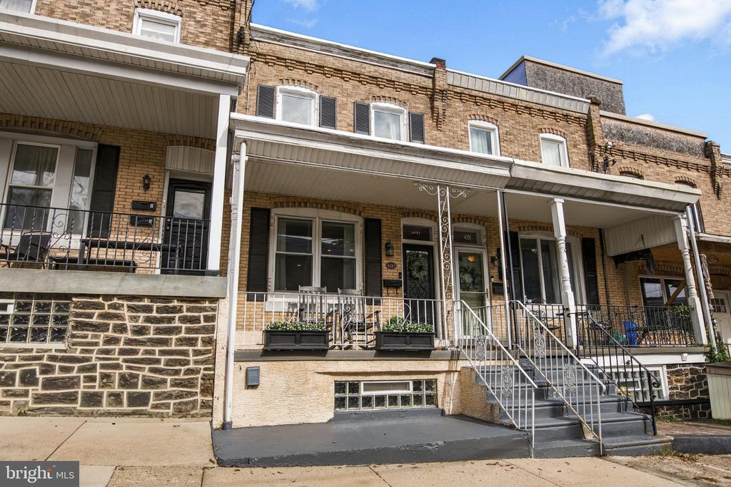 Brick rowhouses with covered porches, iron railings, planter boxes, and front steps.