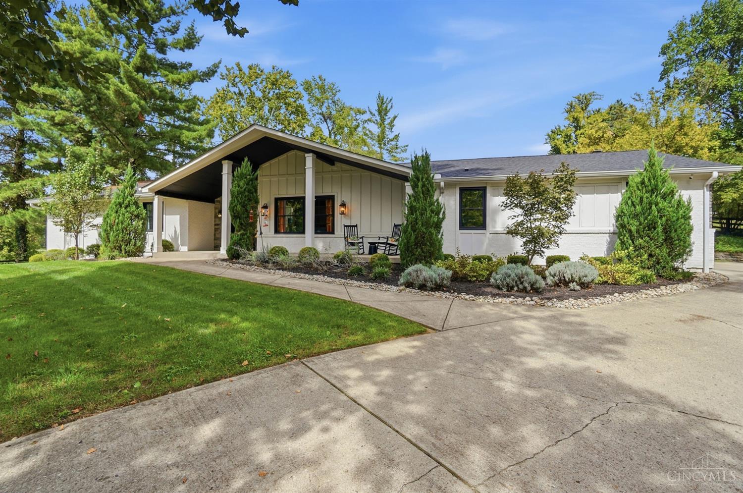 Single-story white brick and sage-sided home with a covered entry and landscaped front yard.