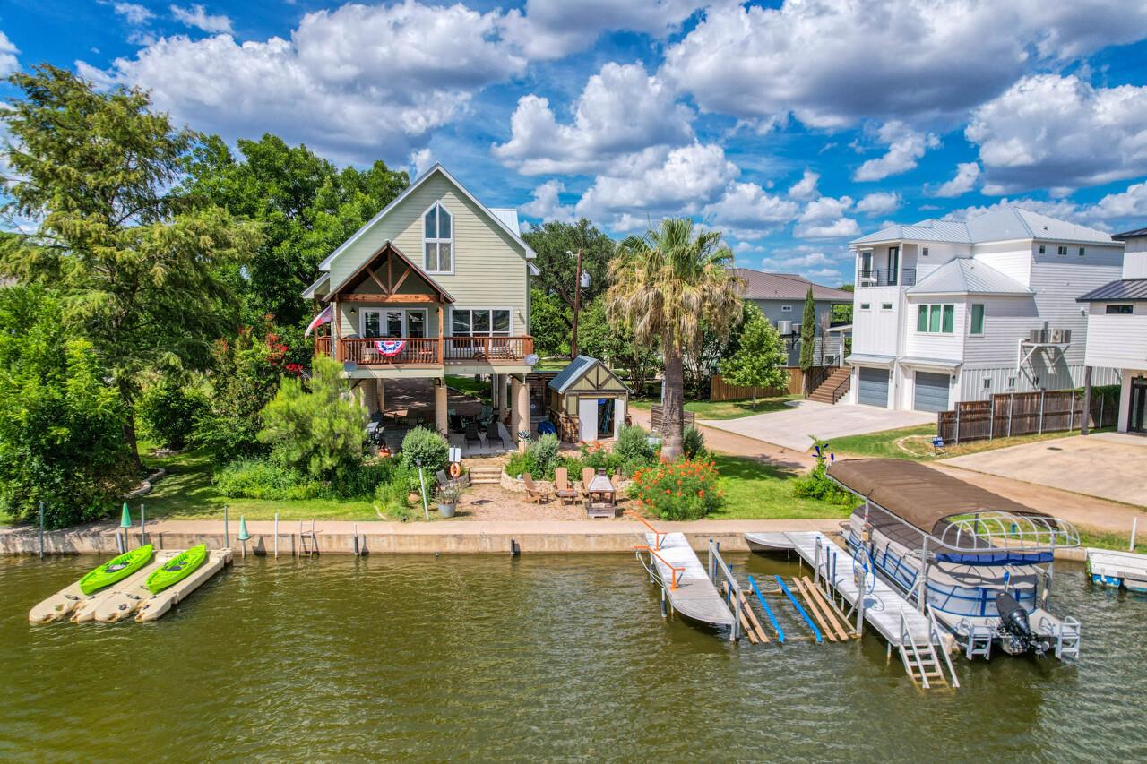 Waterfront home with a raised deck, dock, kayaks, and boat lift.