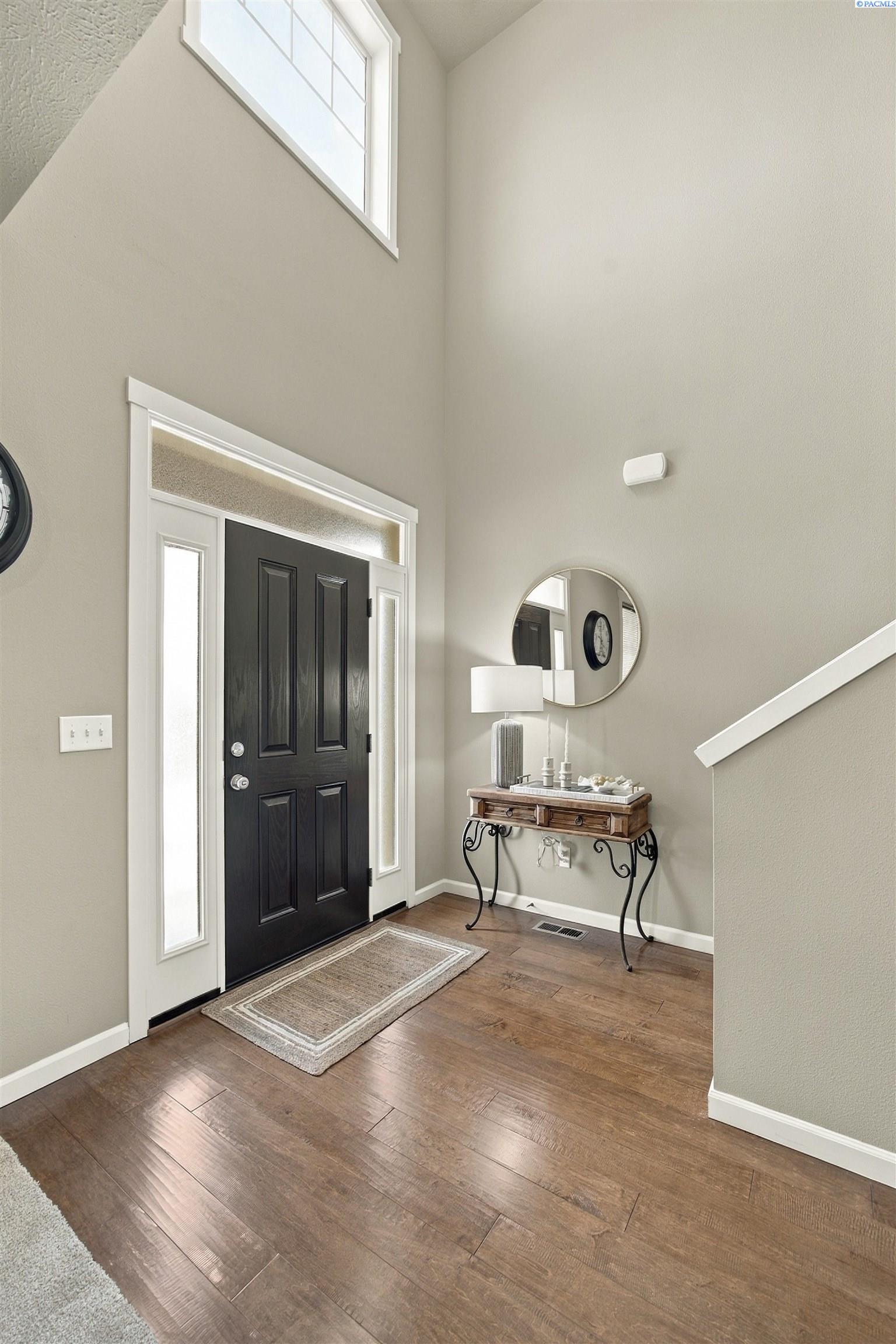 Entry foyer with a tall black front door, high window, and console table beneath a round mirror.