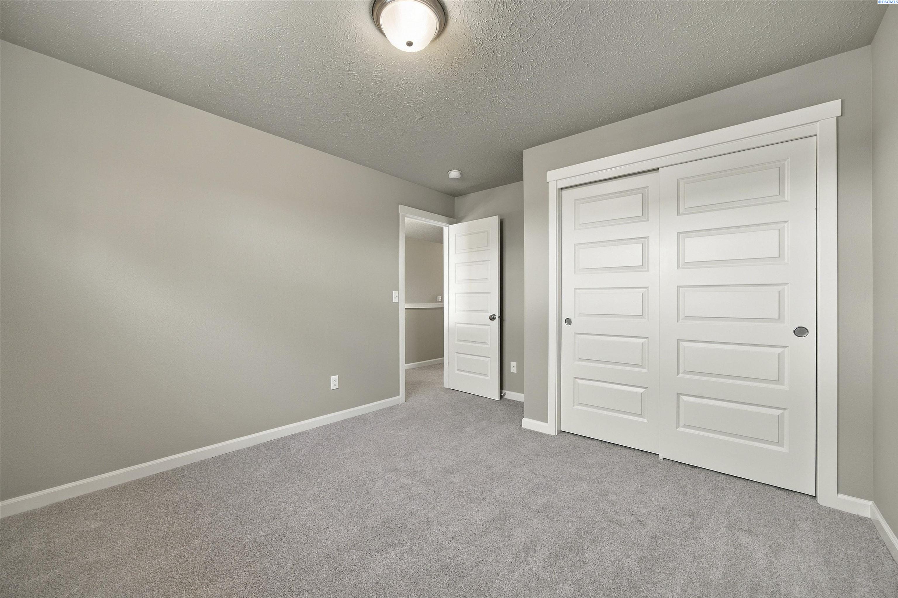 Empty carpeted bedroom with a large white sliding-door closet.