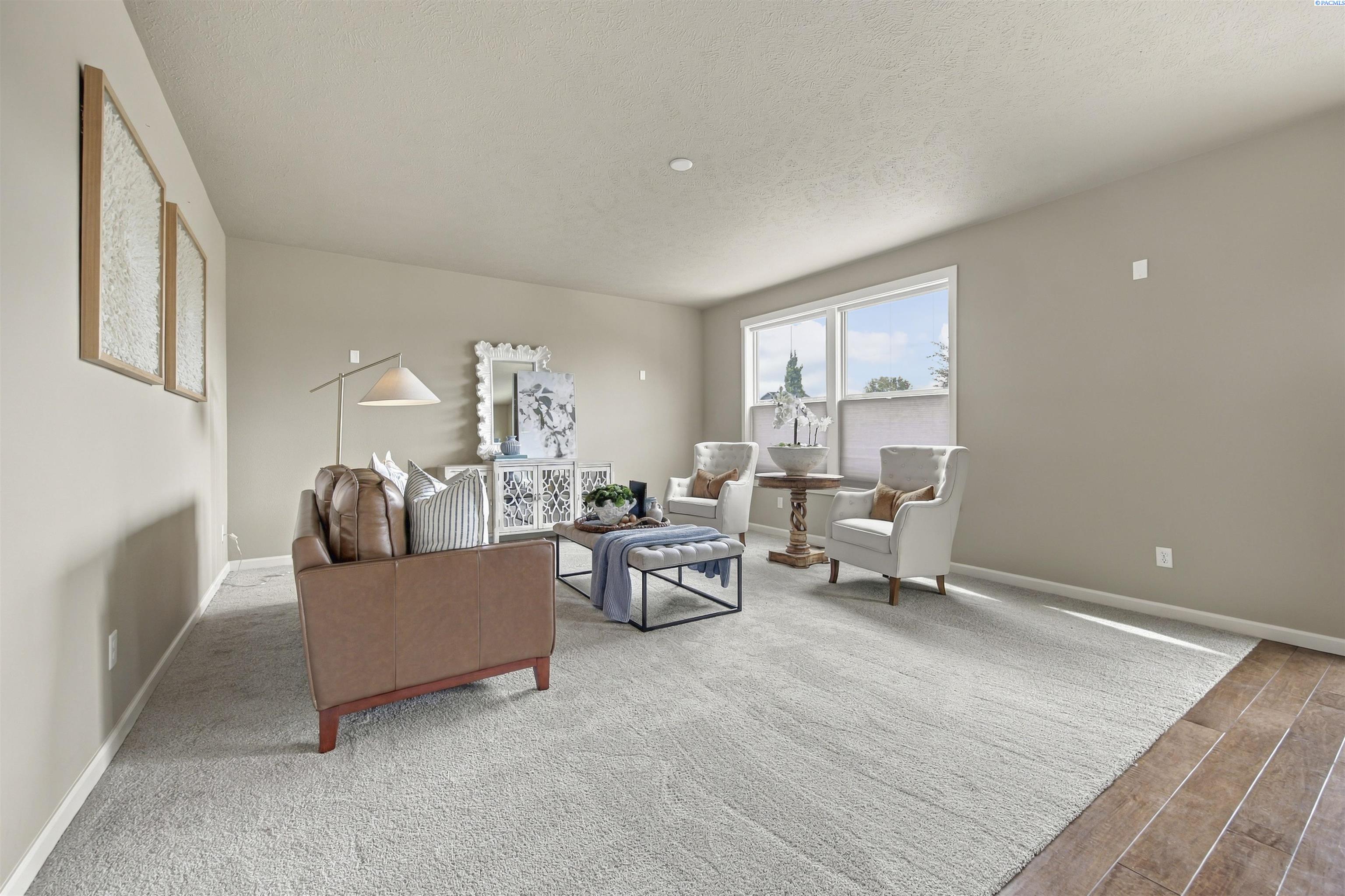 Staged living room with a brown leather sofa, white armchairs, and large light-gray rug.