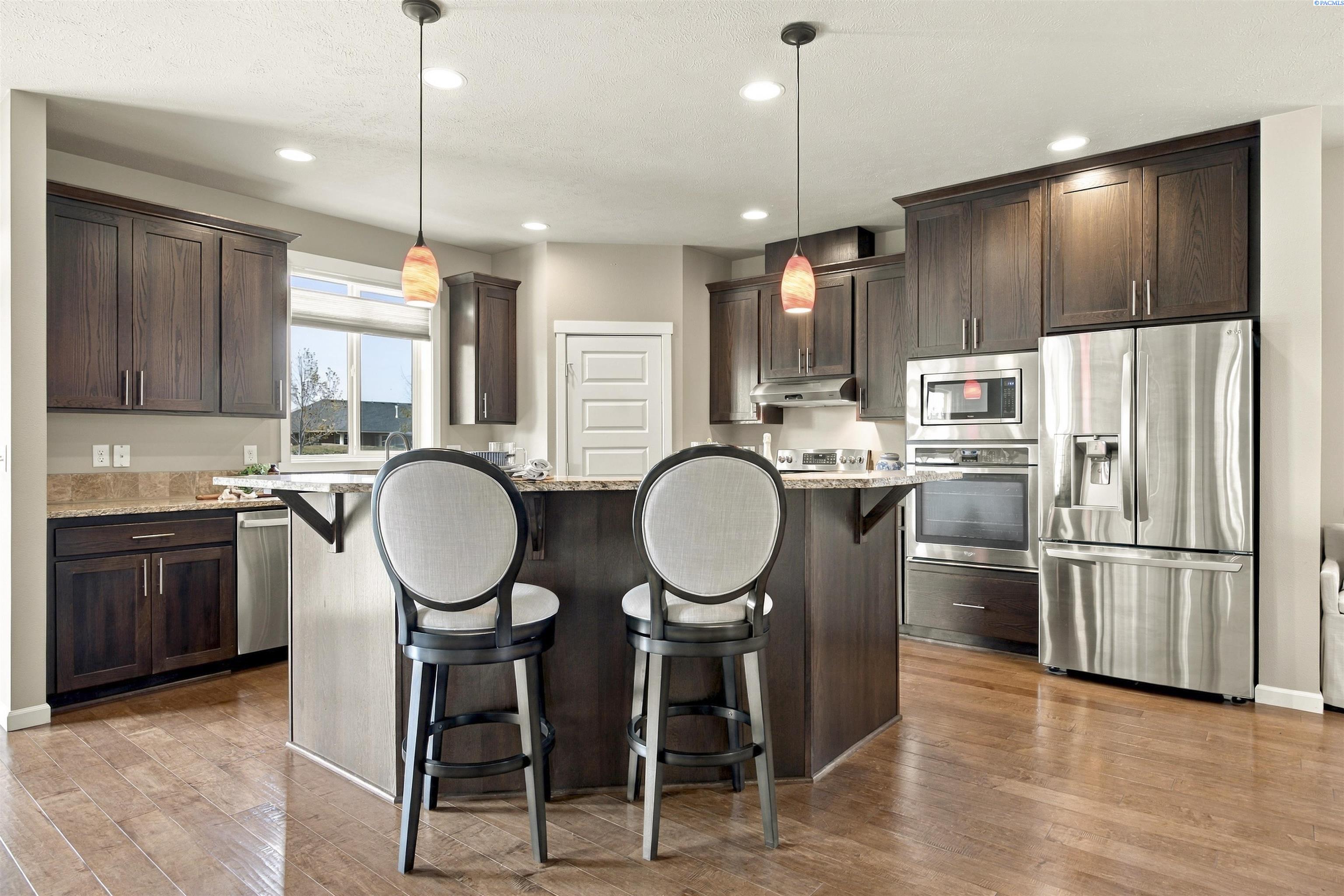 Kitchen with dark wood cabinets, stainless steel appliances, and an island with two bar stools.