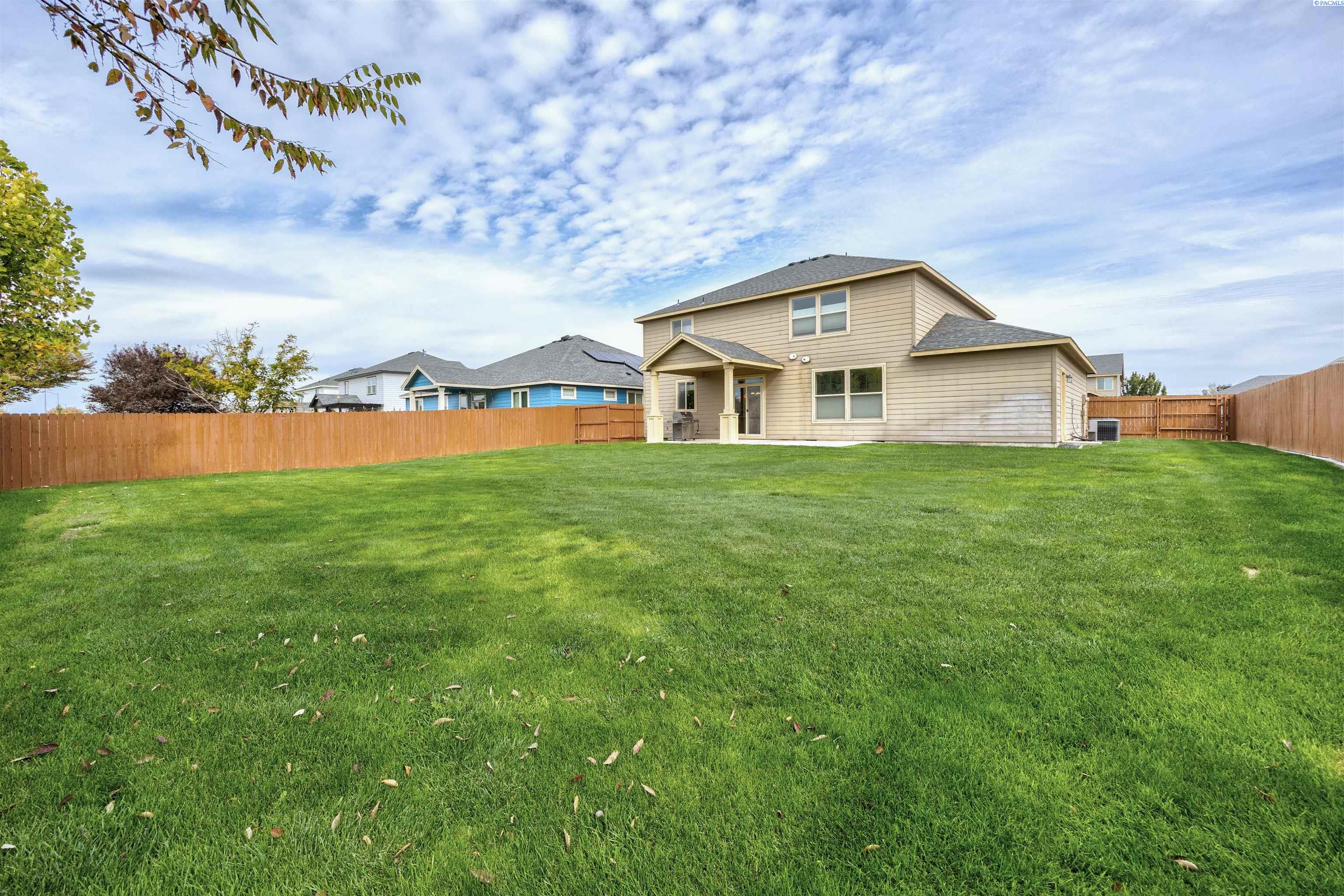 Two-story home behind a broad fenced lawn, with a small covered patio.
