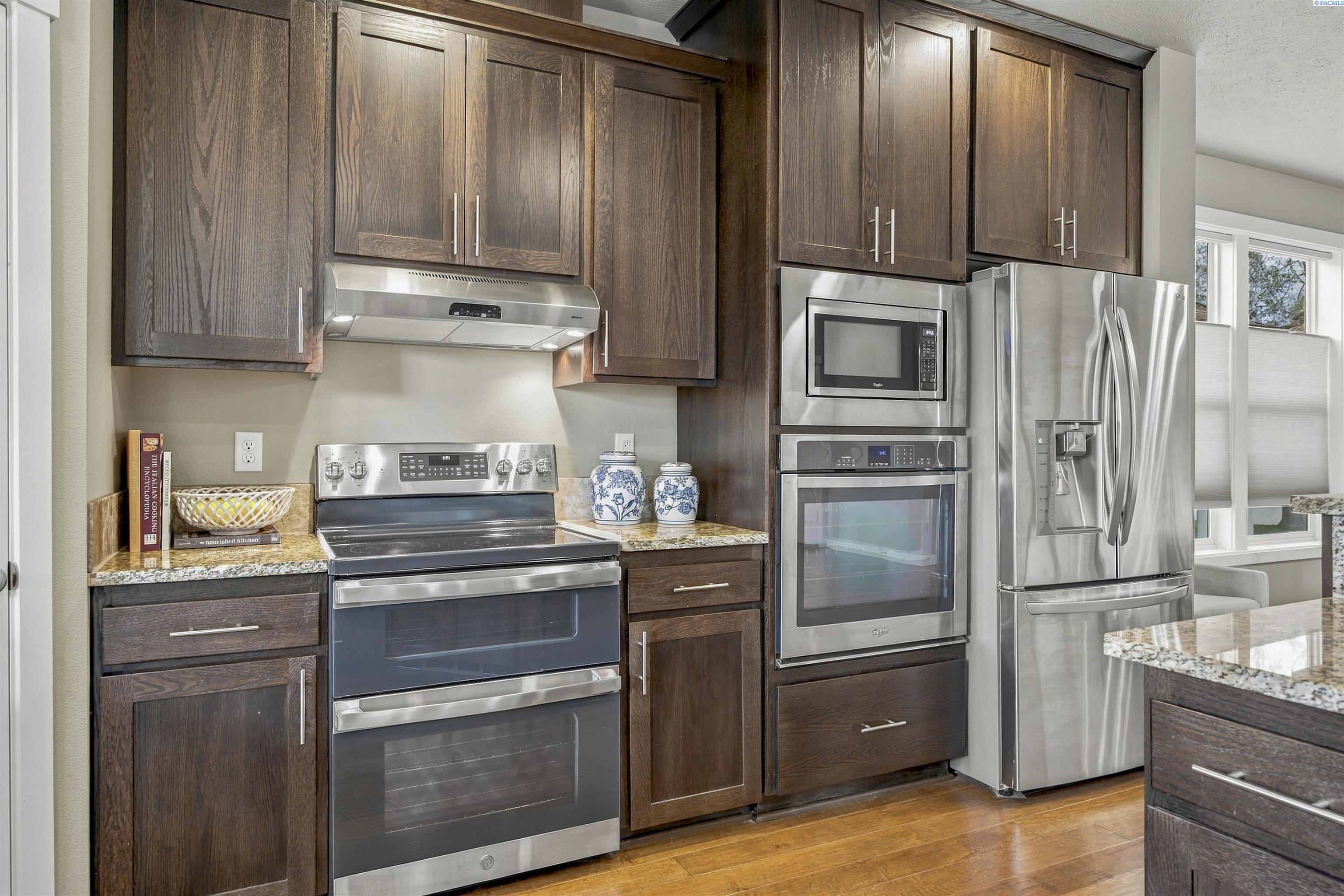 Kitchen with dark wood cabinets, granite counters, and stainless steel appliances.