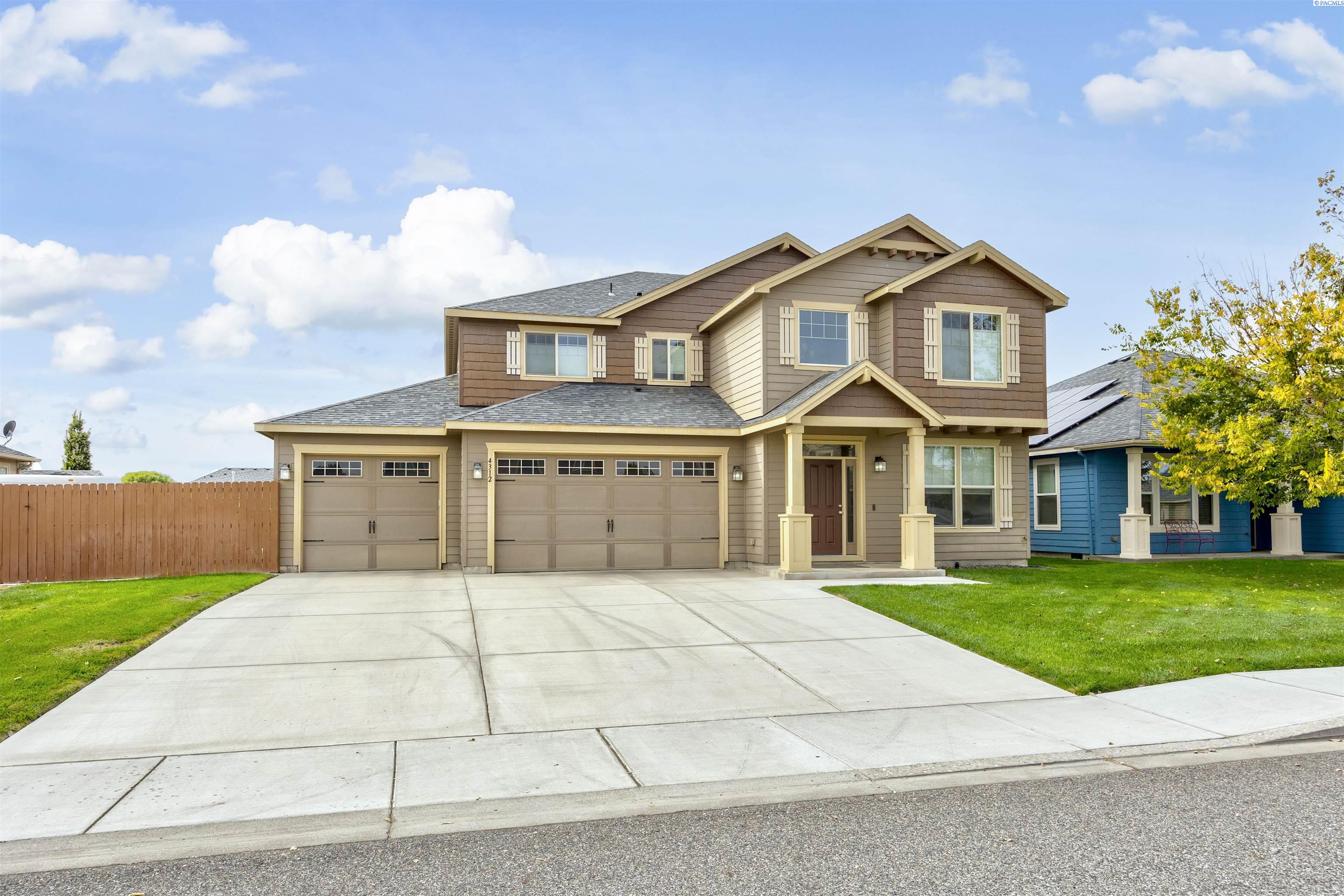 Two-story brown and tan house with a covered entry, two garage doors, and a broad concrete driveway.